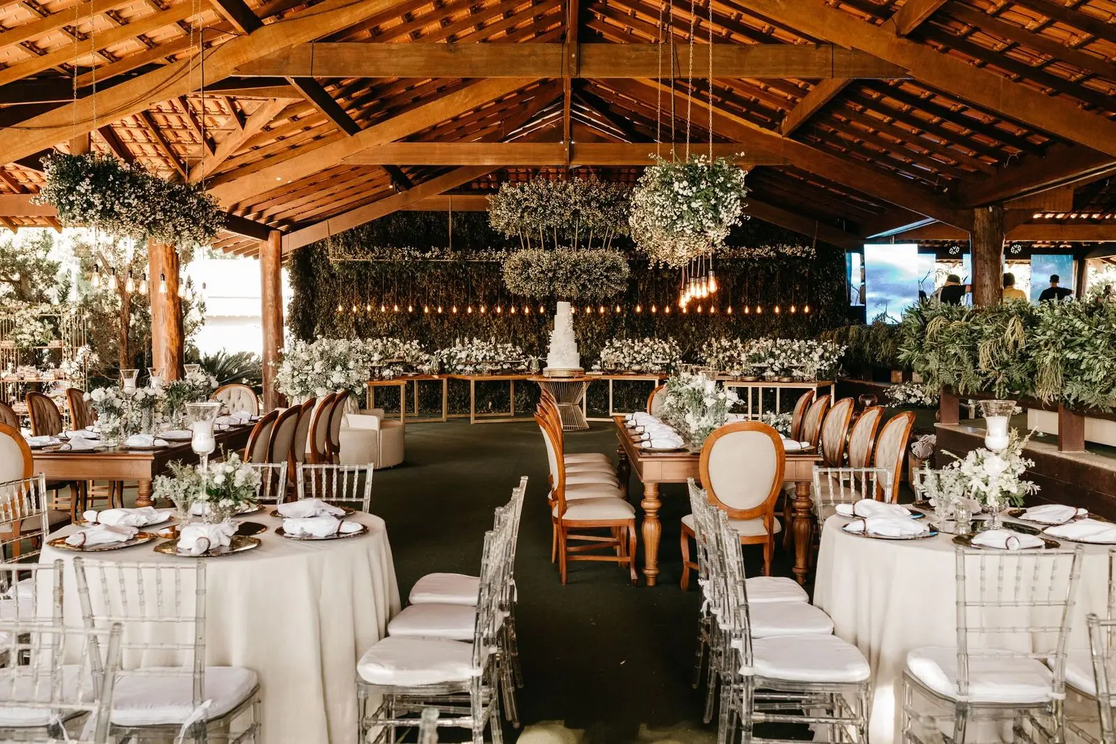 Wedding reception under a timber pavilion with hanging greenery and candlelight