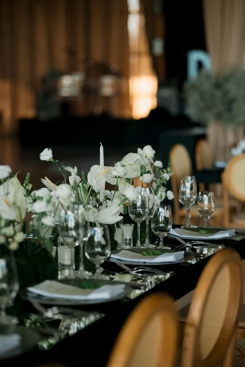 Long banquet table with white florals, taper candles and gilded chairs