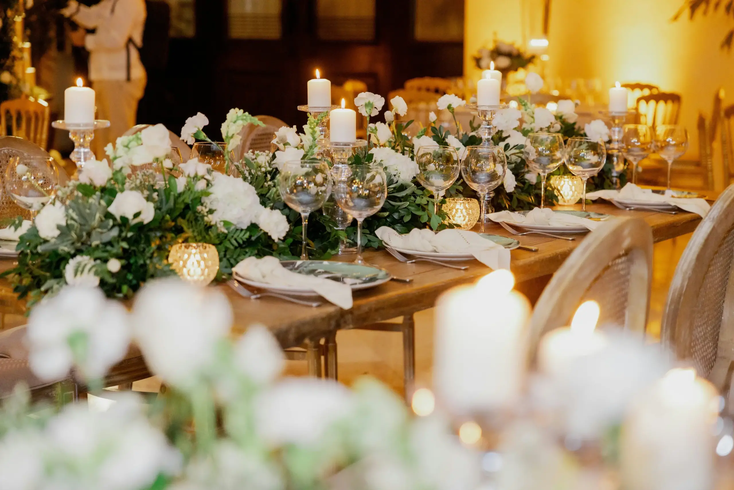 Candlelit banquet table with a garland of greenery and white roses
