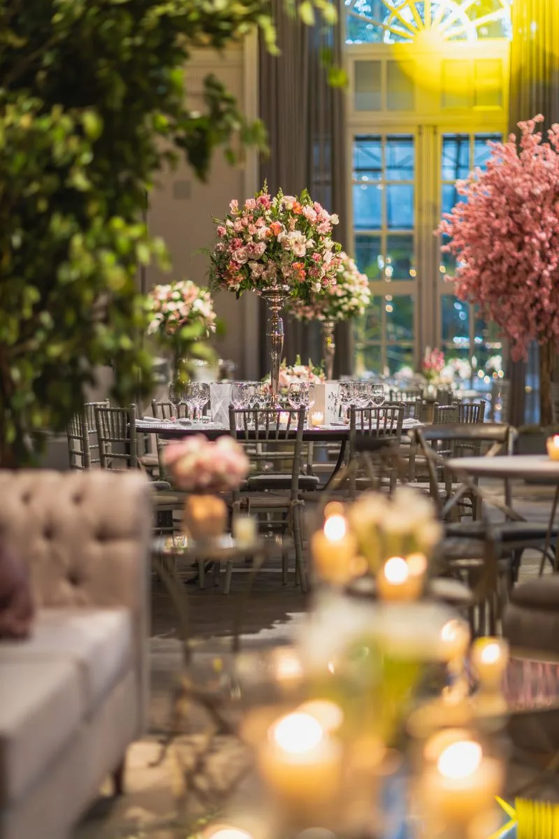 Grand hall arranged with tall pink floral centrepieces and candlelight