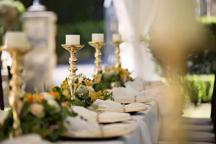 Table styled with gold candlesticks and a runner of greenery