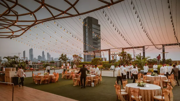 Rooftop event with string lights and a city skyline behind