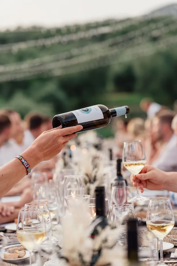 Wine being poured at a long outdoor table in the countryside