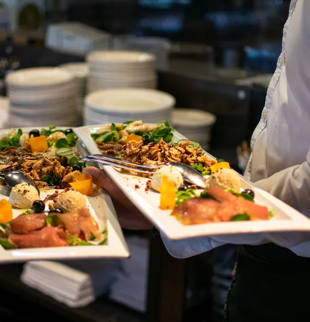 Server carrying plated salmon appetisers out of the kitchen
