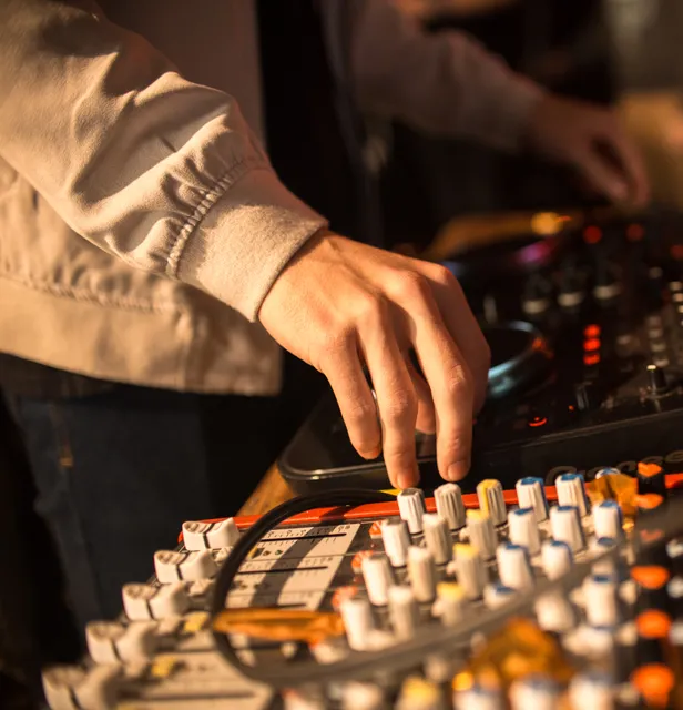 DJ mixing at a controller and sound desk during an event
